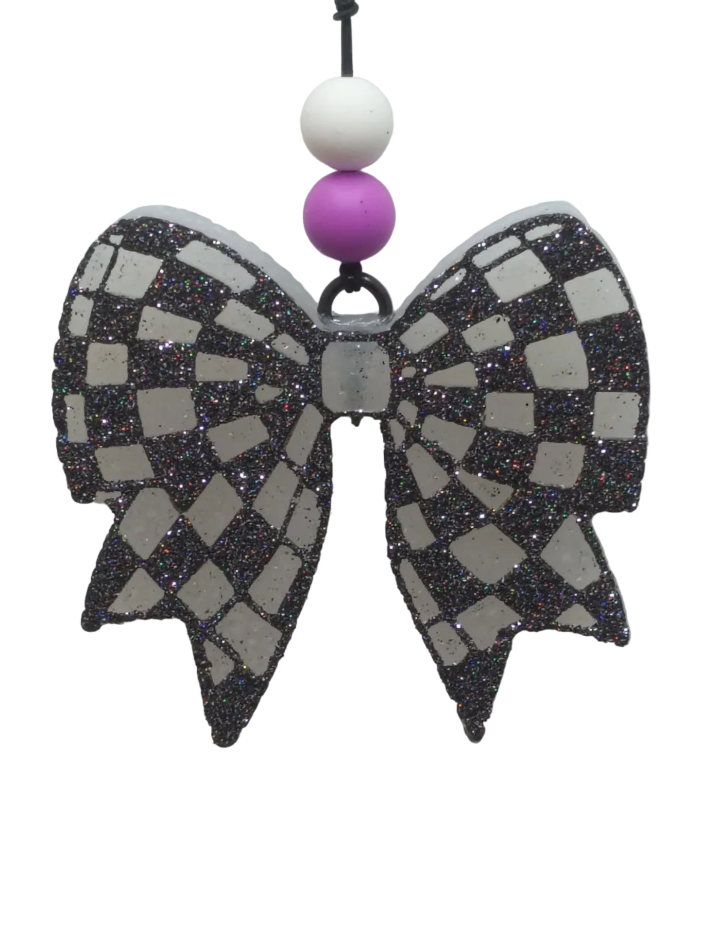 Decorative Bow shaped car air freshener with checkered pattern in black glitter on a white base. purple and whte beads decorate the elastic hanger. 