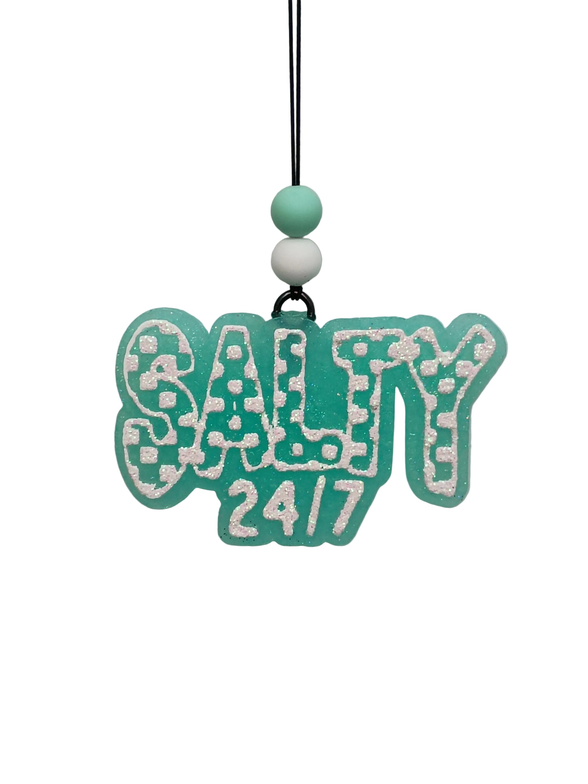 Hanging car air freshener with checkered design lettering that says  'salty 24/7'  in white glitter on a mint green base.  Mint and white beads decorate the elastic hanger. 